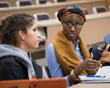 Two students have a conversation in a law classroom.